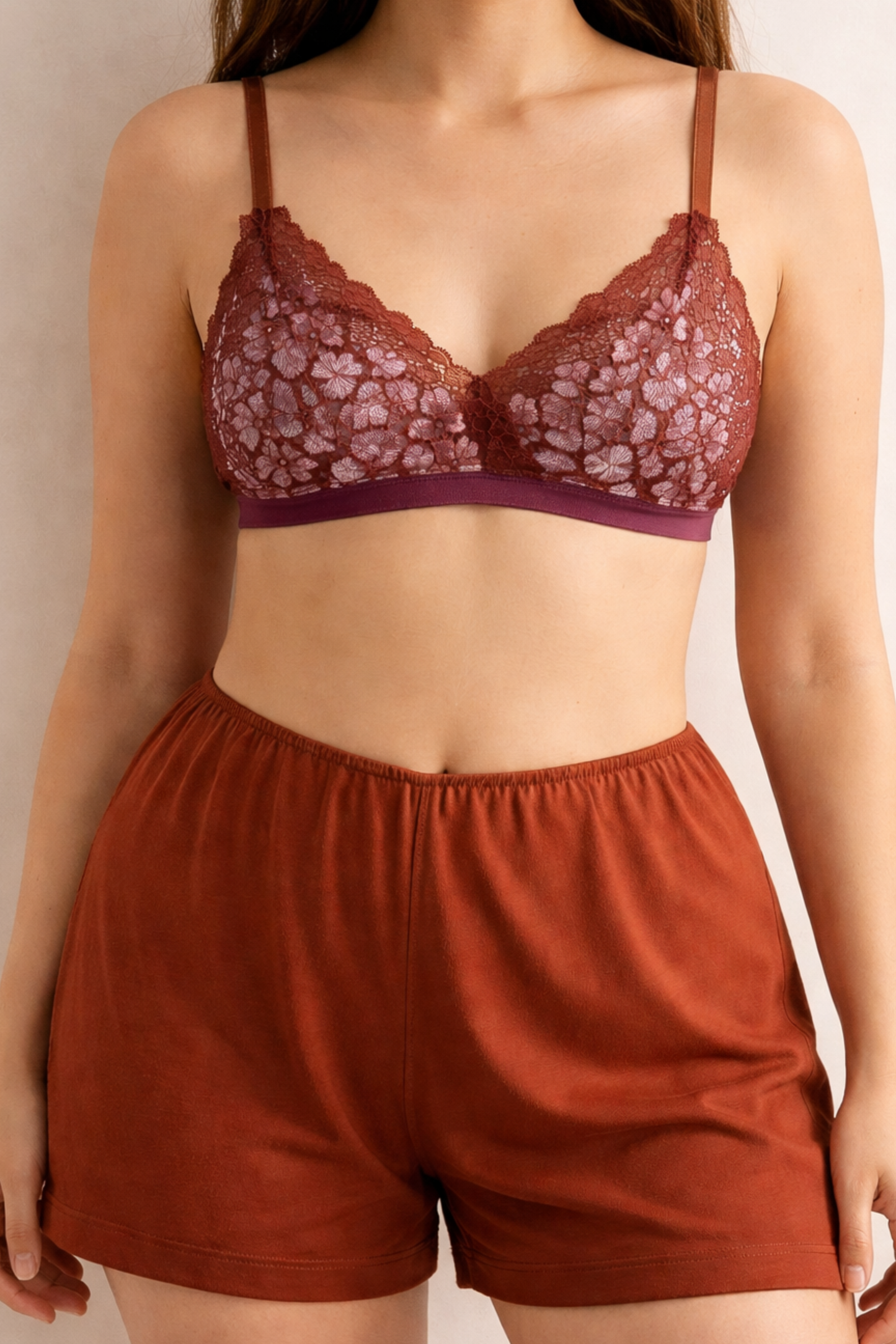 Front view of an airy cocoa-lilac wire-free lace bralette with soft triangle cups, worn with spiced terracotta shorts. Lightweight, breathable, and gently supportive.