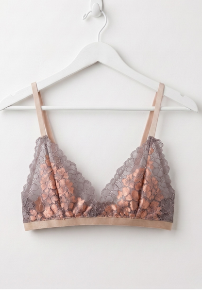 Rose gold lace bralette on a white hanger against a white background
