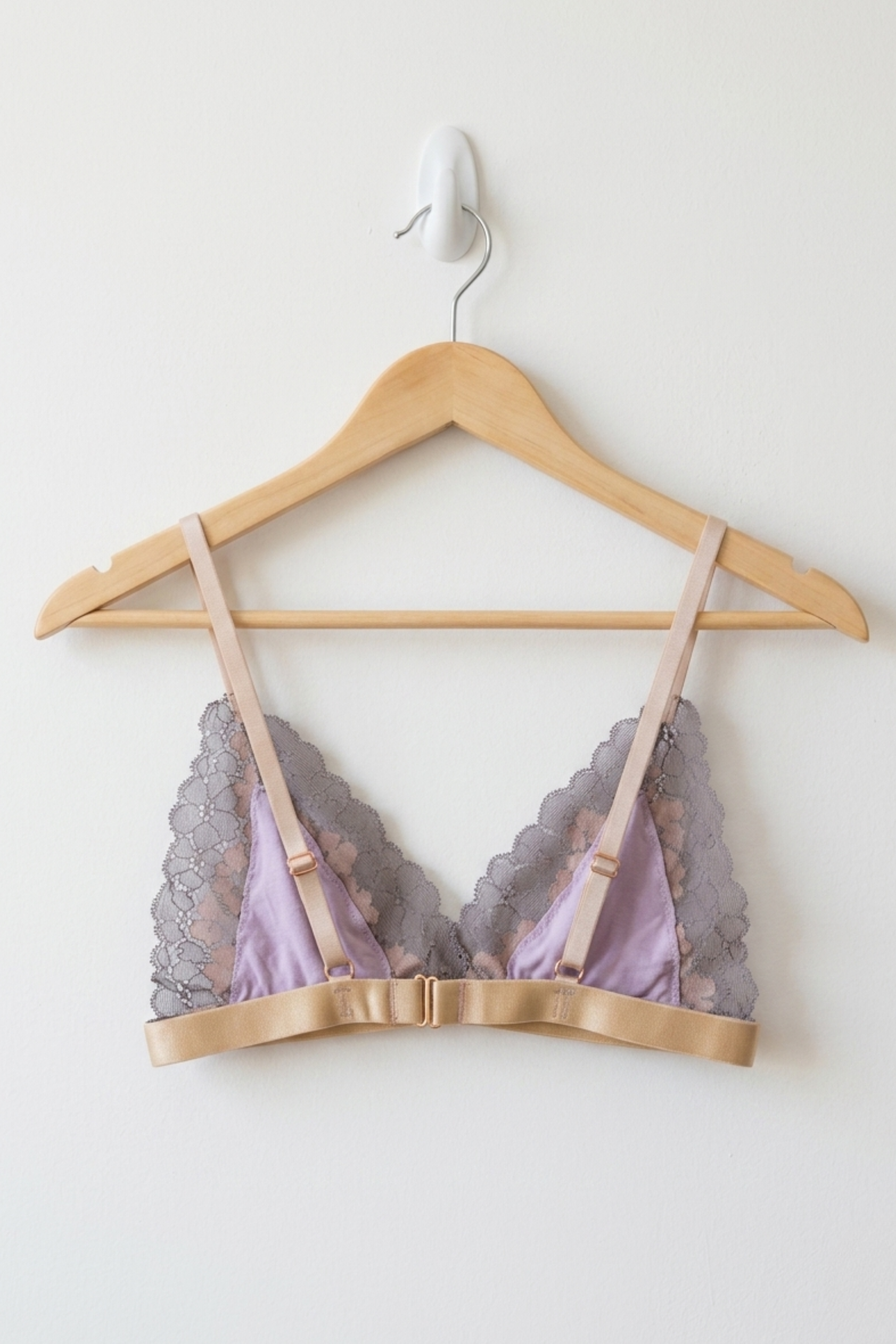 Lace-trimmed bralette with pink straps on a wooden hanger against a white background