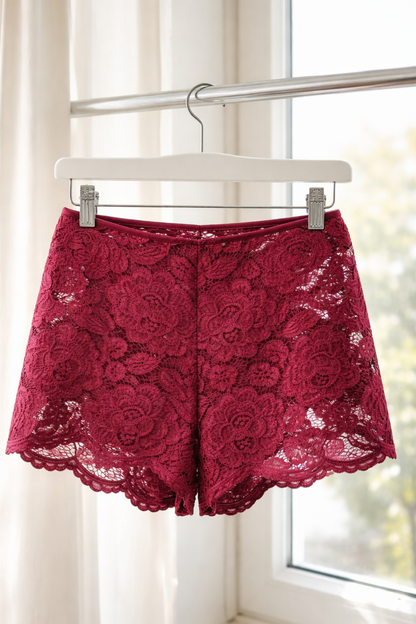 Burgundy floral lace shorts hanging on a white hanger, showing delicate lace texture and scalloped edges.