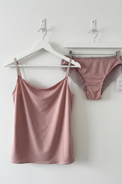 Cuurve Calm Clara cowl neck cami in Blush, soft modal jersey, with sleek sophie in Dawn lace, hanging on white hanger against white wall