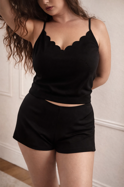 Woman wearing a black lace-trimmed top and shorts against a neutral background