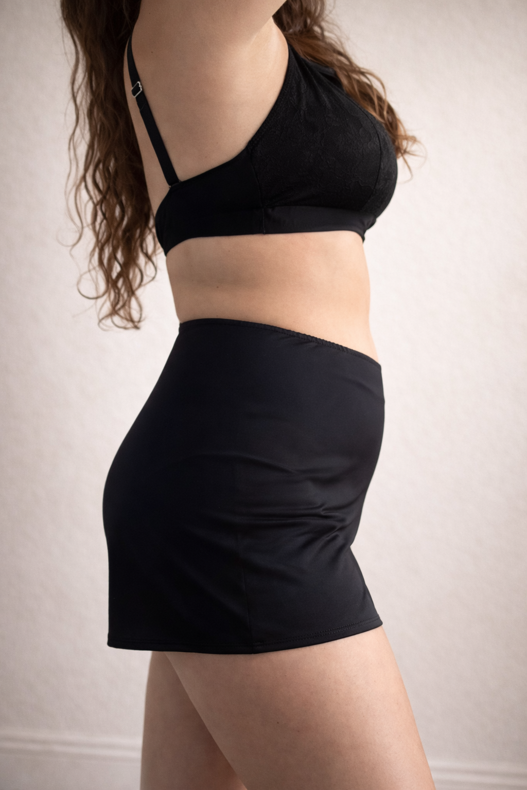 Person wearing a black bikini set against a neutral background