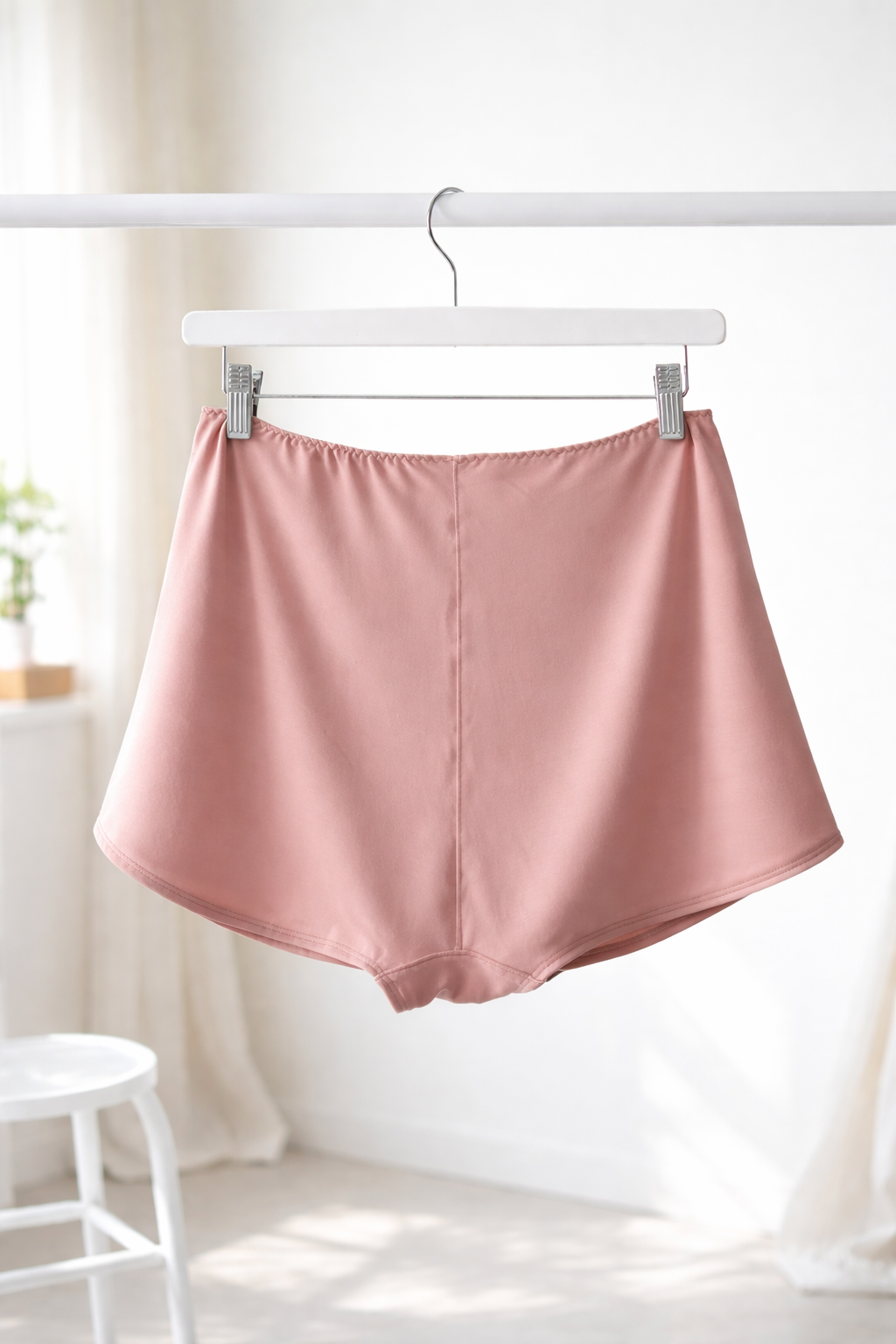 Cuurve Cosy Charlotte Shorts in Blush modal jersey, hanging on a clothes hanger against a bright minimal background