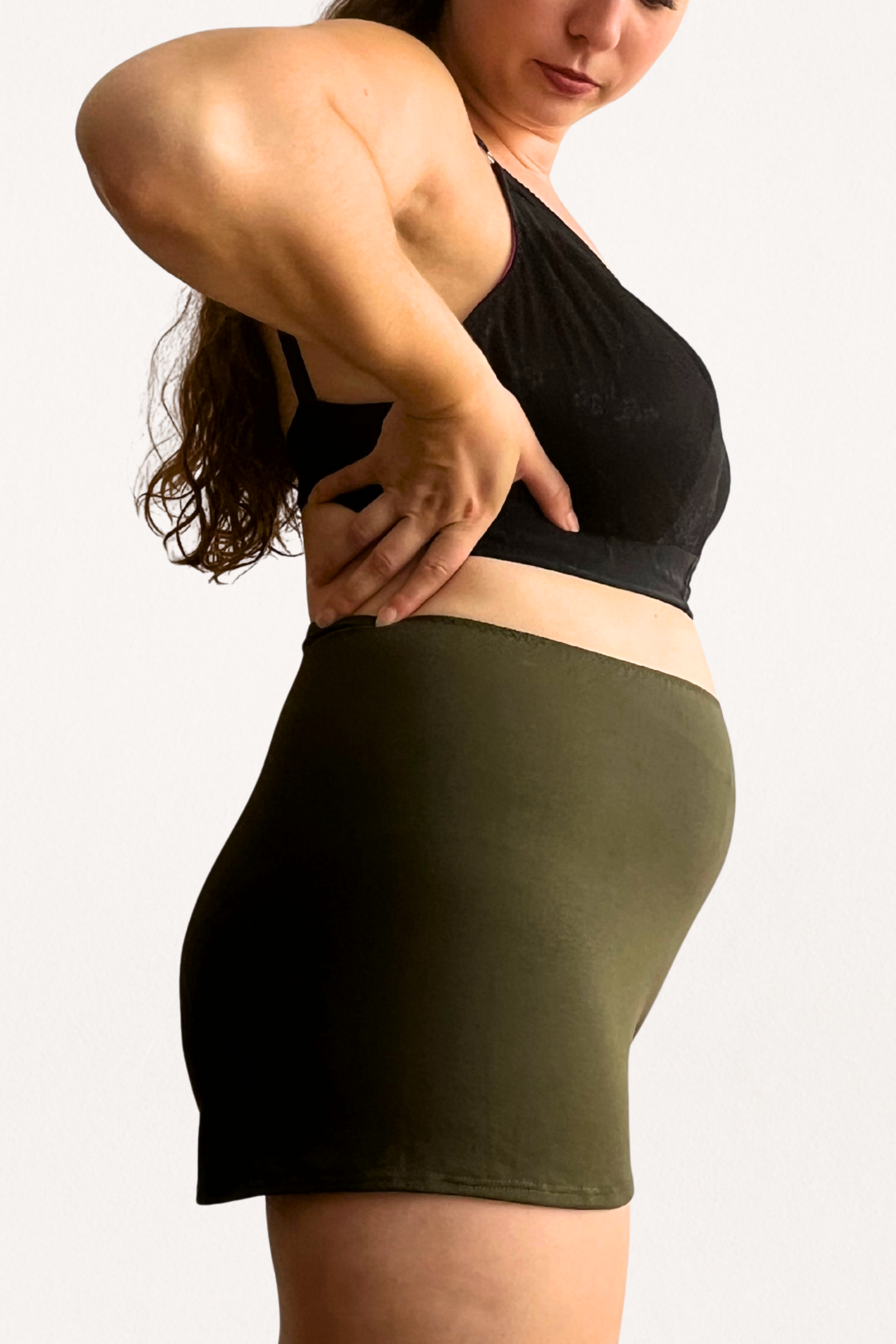 Woman wearing a black sports bra and comfortable dark olive shorts from modal jersey on a white background