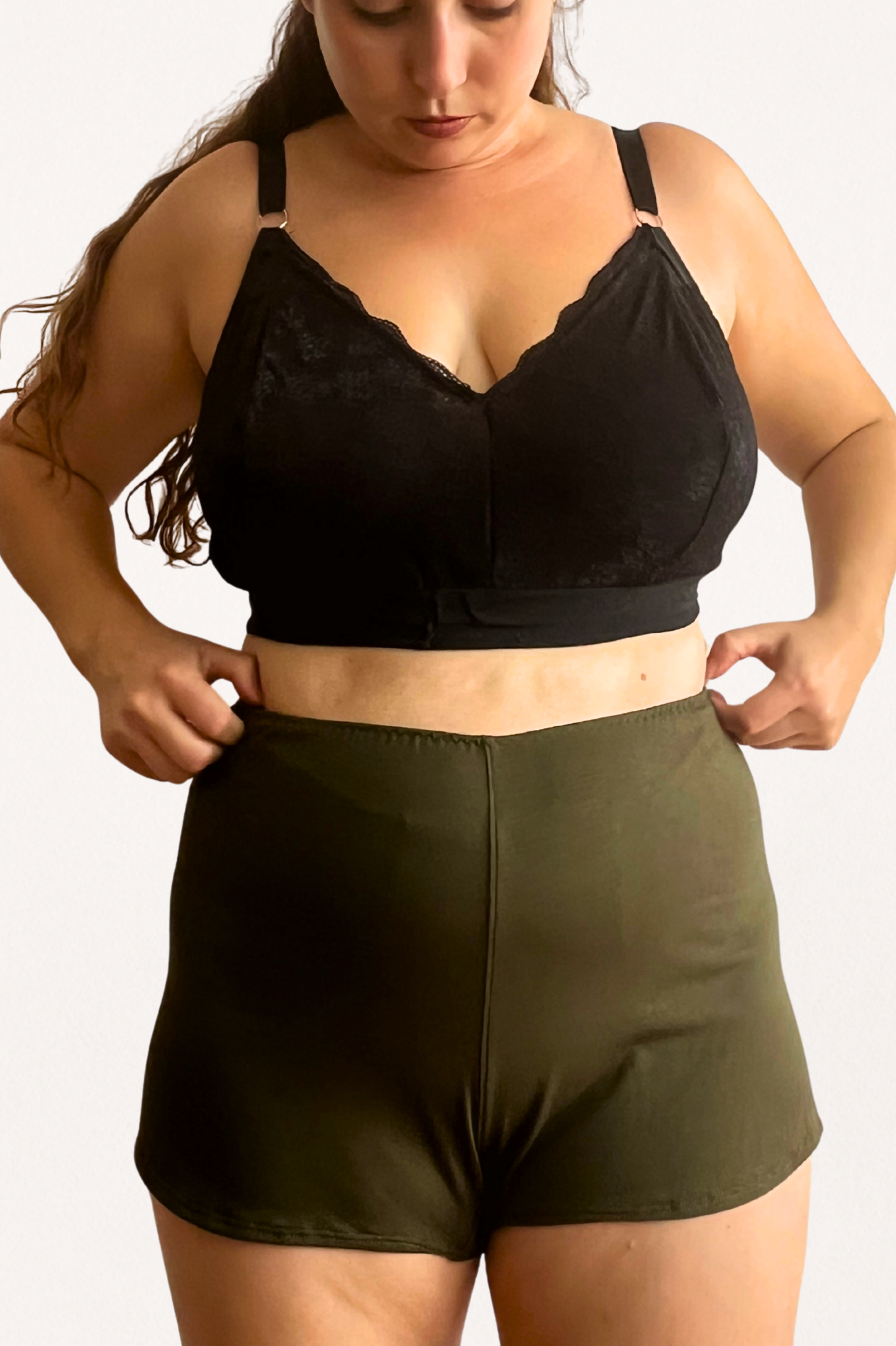 Woman wearing a black lace bralette and green modal tencel shorts on a white background