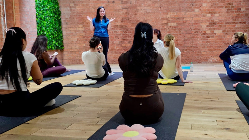 Group yoga class in a studio with a teacher leading the session.