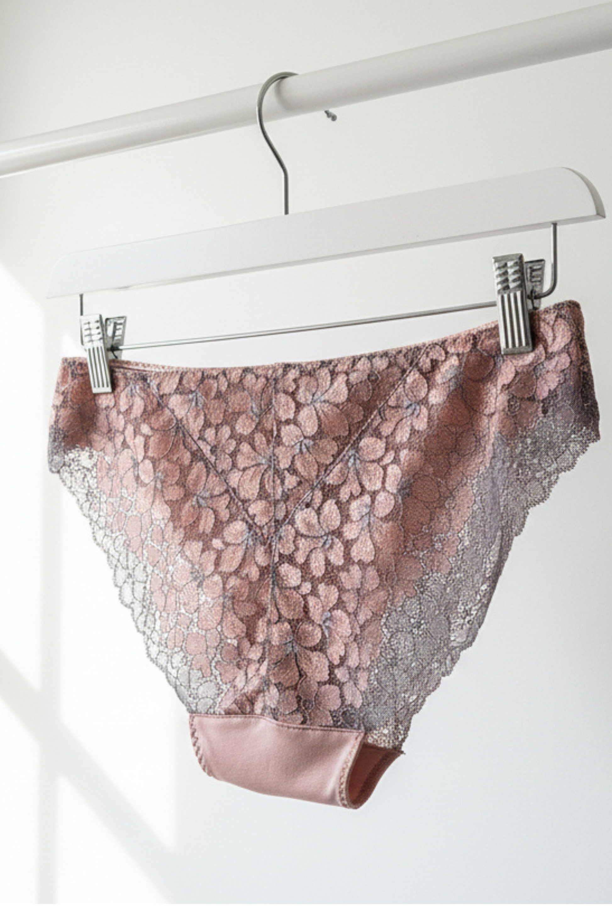 Handcrafted UK lingerie brief in blush pink, soft rose and silver dawn lace, Cuurve Sleek Sophie, hanging on rail in natural light