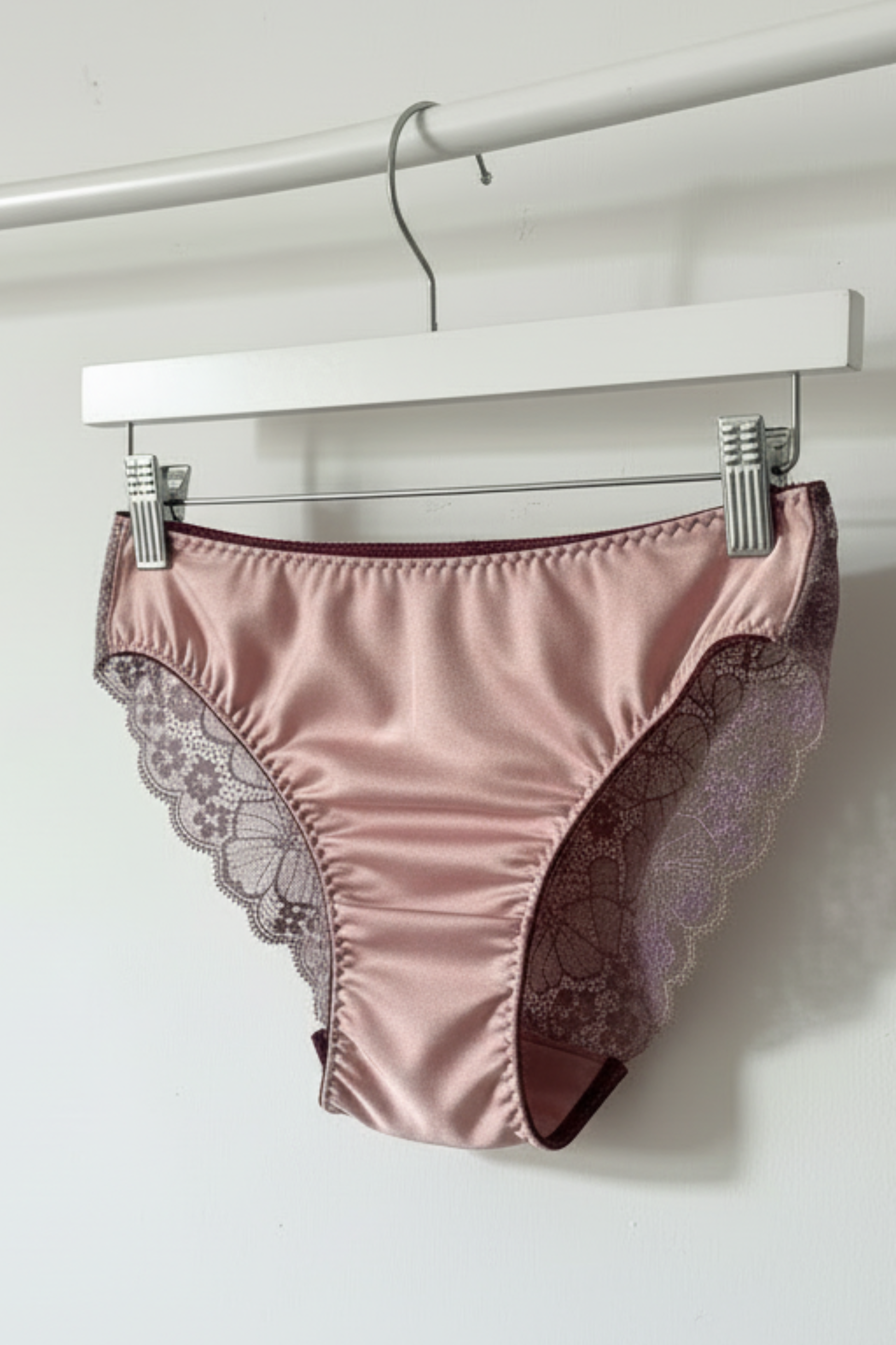 Handcrafted UK lingerie brief in blush pink and dusk lace, deep violet lace with gold trim detail, Cuurve Sleek Sophie, hanging on rail in natural light