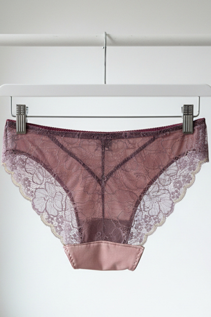 Handcrafted UK lingerie brief in blush pink and dusk lace, deep violet lace with gold trim detail, Cuurve Sleek Sophie, back view hanging on rail in natural light