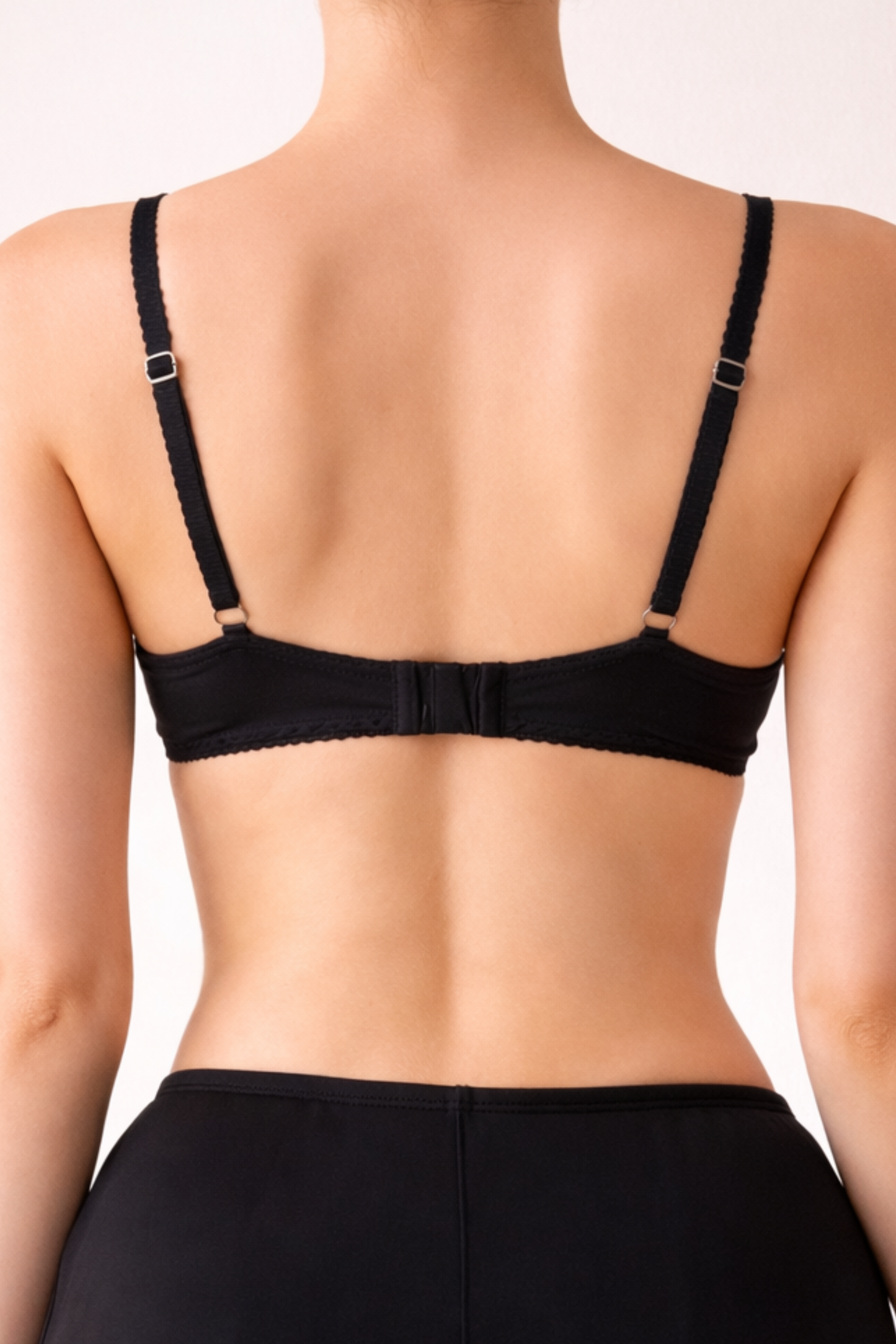 Back view of a soft black wire-free lace bra worn on a model, showing adjustable straps and a smooth supportive band.