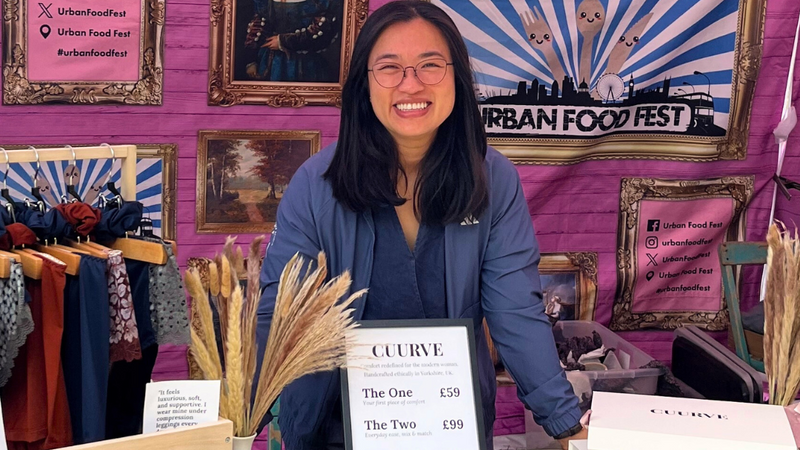 Woman standing behind a table with 'Cuurve' products at an Urban Food Fest booth.