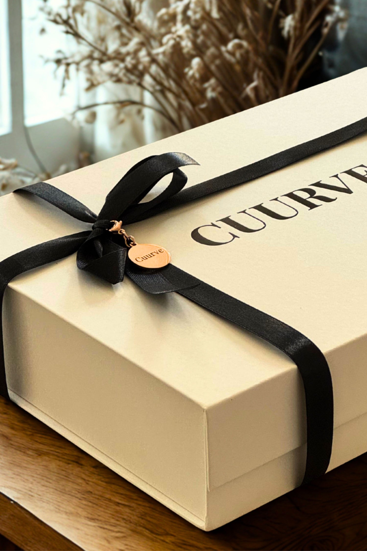 Cuurve rose-gold and cream gift box tied with black ribbon — slow-fashion packaging for the Olive Gift Set pajama shorts.