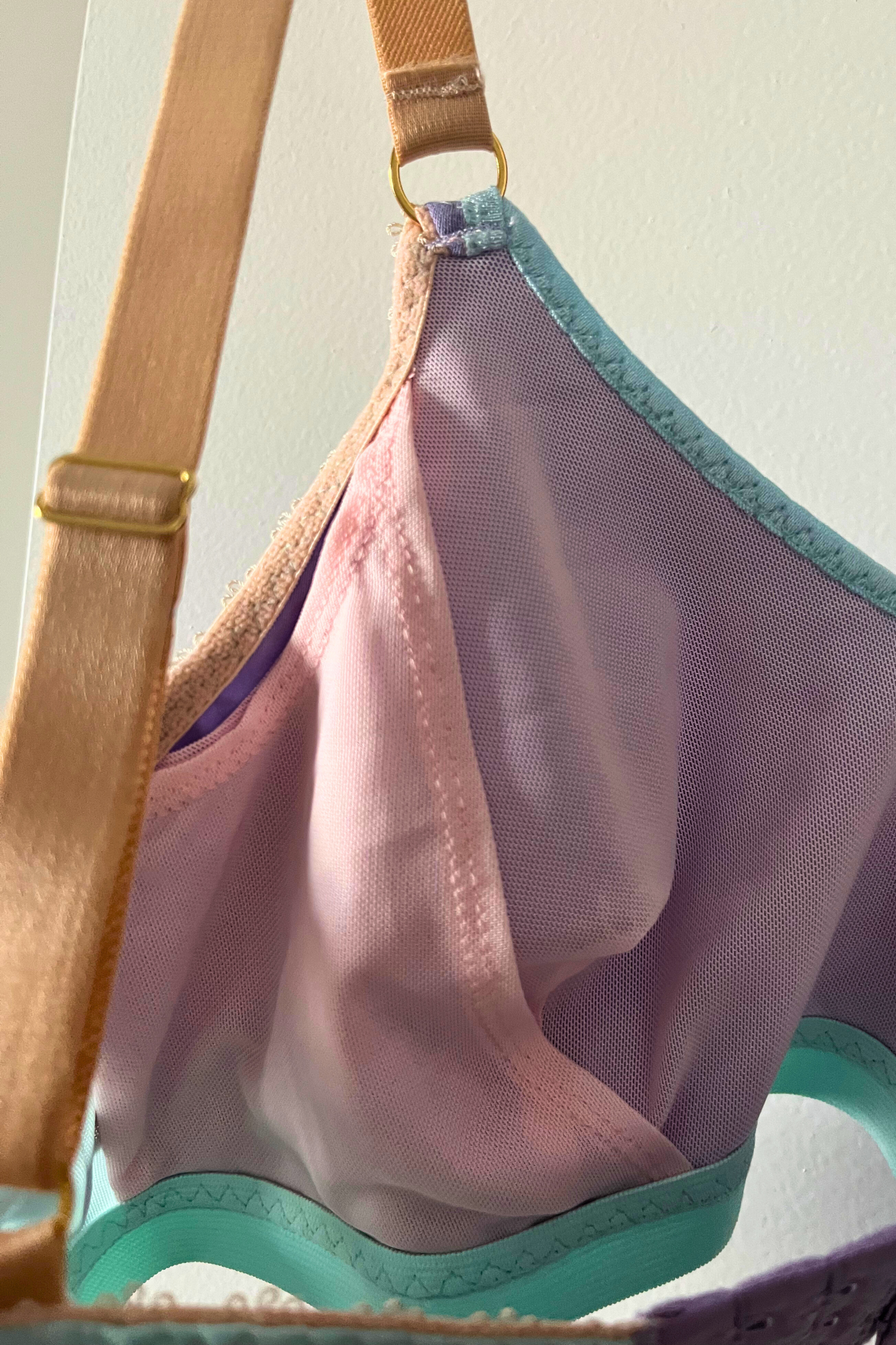 close-up side view of the round-neck bralette showing aqua mesh panel, lilac cotton jersey, and internal mesh sling area.