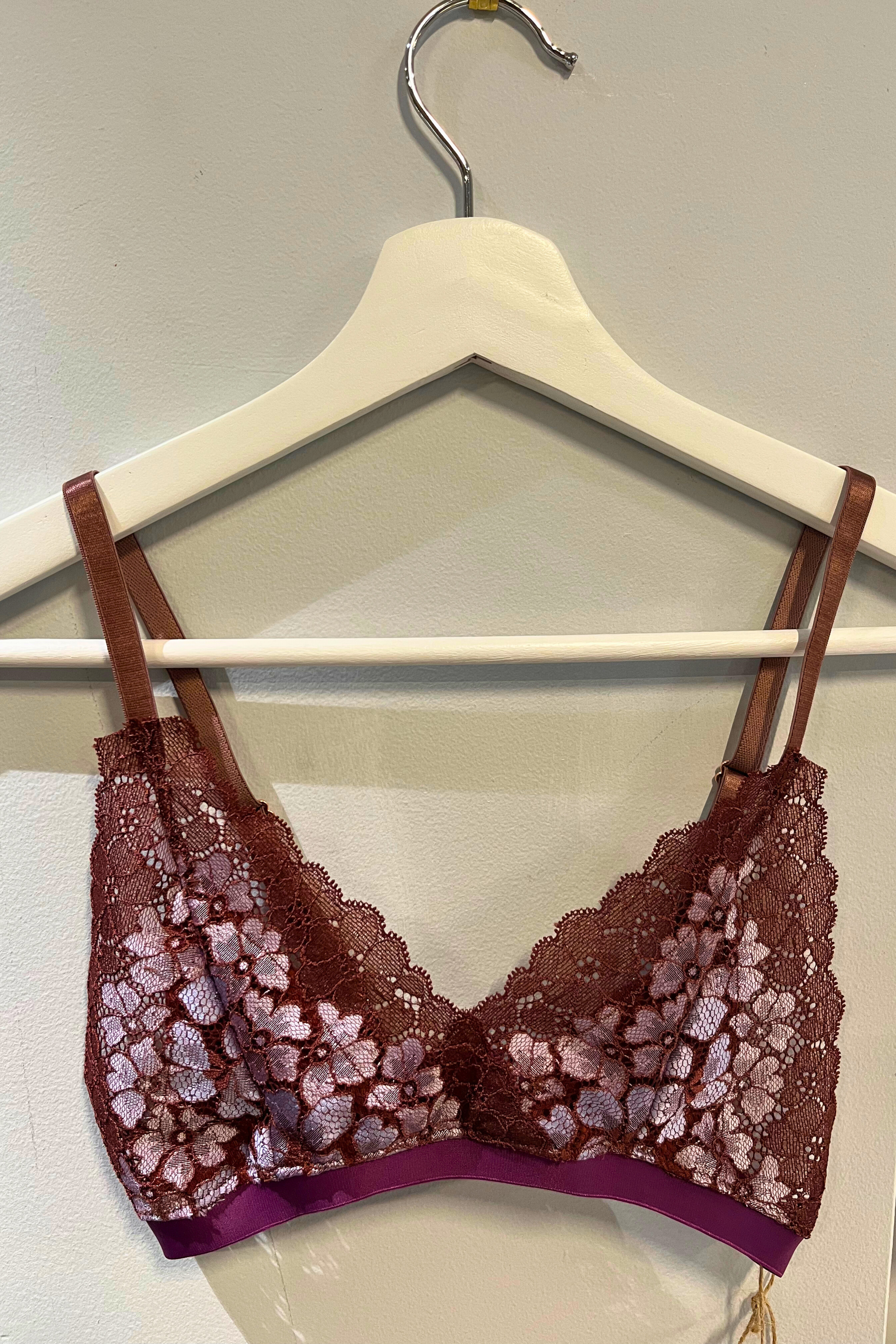 hand-sewn metallic cocoa and lilac lace bralette hanging on a white hanger, showing the dual-tone metallic lace and micromodal nipple-cover lining against a soft studio background.