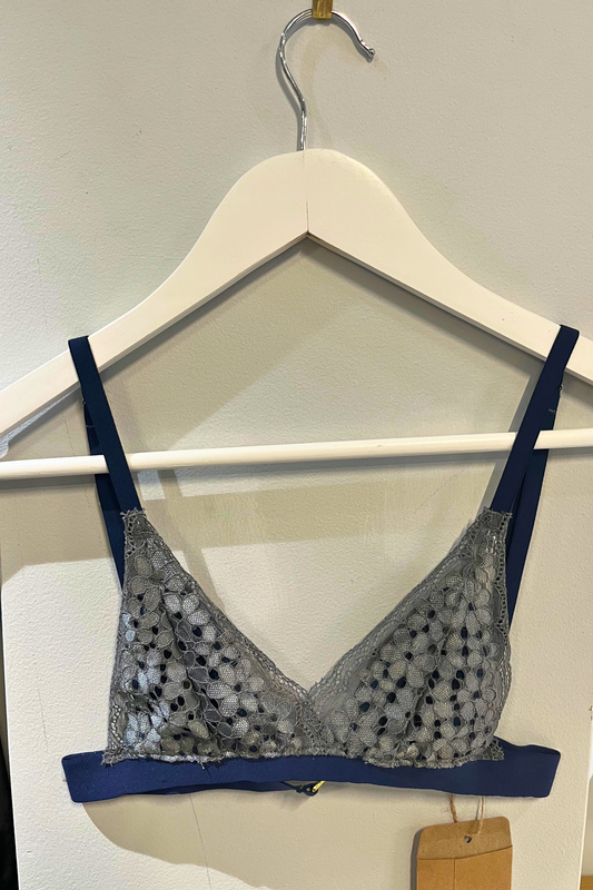 hand-sewn navy lace bralette on a white hanger, showing the delicate lace cups, micromodal nipple-cover lining and slim navy straps.