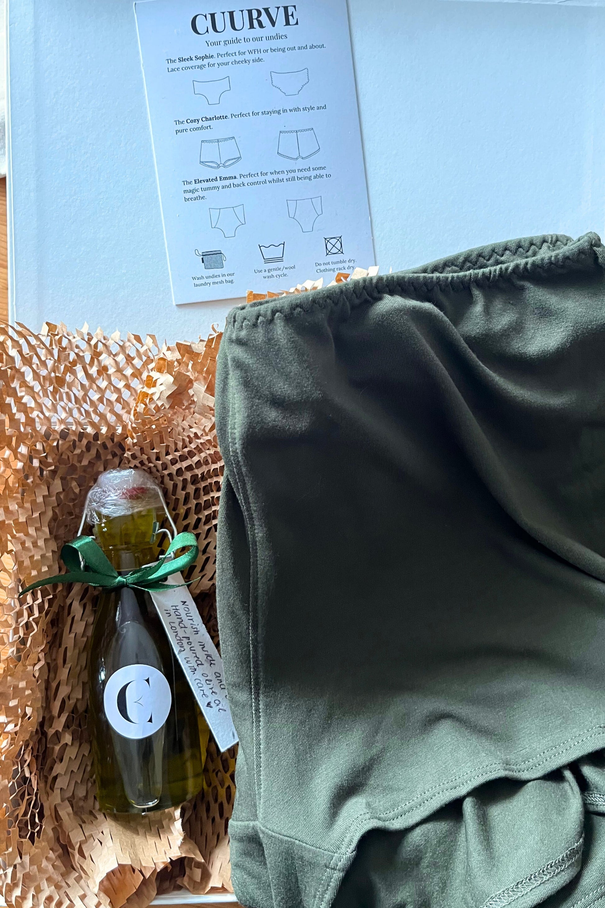 Cuurve Olive Gift Set with Cosy Charlotte pajama shorts and Greek Nikolaos olive oil bottle tied with ribbon — inspired by Cretan harvest and handmade care.