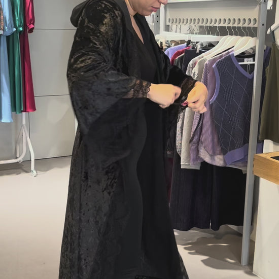 Video of the black crushed velvet romantasy gown being worn, showing the lace-trimmed hood and bell sleeves