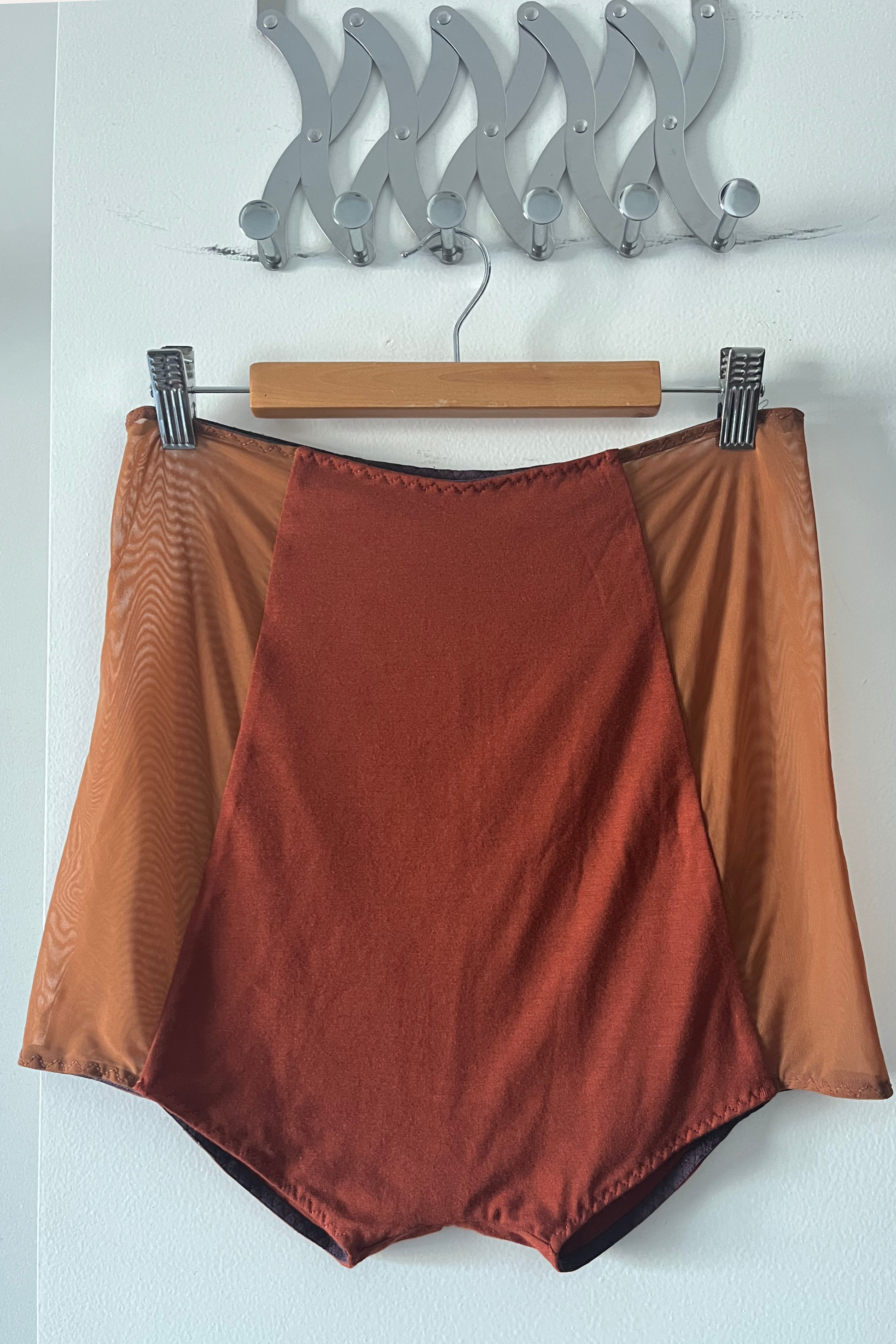 alternate side of the reversible micromodal panty in rust, displayed on a hanger, showing the second micromodal face and mesh side panels.