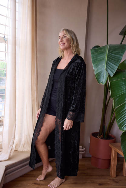 Model wearing the black velvet romantasy gown open over black sleepwear, full length